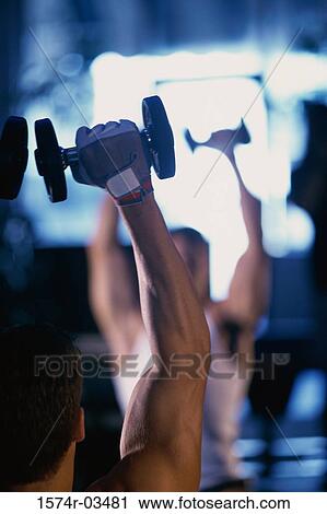 Young man exercising with dumbbells View Large Photo Image Stock Image - Young man exercising with dumbbells. Fotosearch