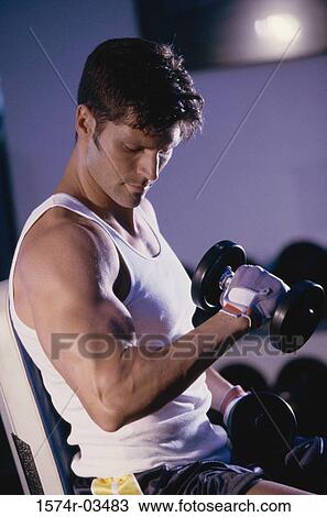 Young man exercising with dumbbells View Large Photo Image Stock Image - Young man exercising with dumbbells. Fotosearch