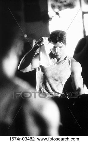 Young man looking down in a health club View Large Photo Image Stock Image - Young man looking down in a health club. Fotosearch
