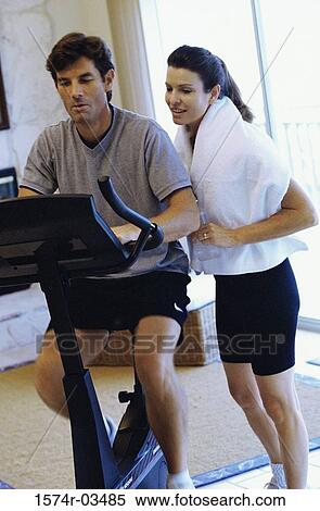 Stock Photography - Young woman and a young man exercising in a gym. Fotosearch