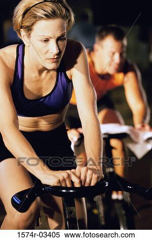 Young woman exercising on a cycling machine View Large Photo Image Stock Photography - Young woman exercising on a cycling machine. Fotosearch
