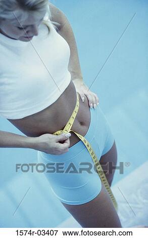 Young woman measuring her waist View Large Photo Image Stock Photo - Young woman measuring her waist. Fotosearch