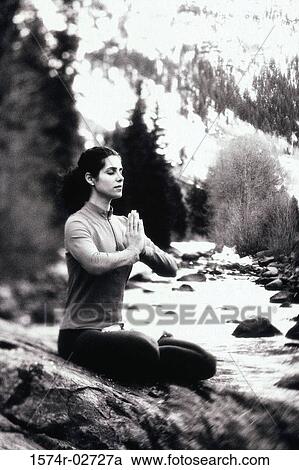 Stock Image - Young woman meditating in the lotus position. Fotosearch