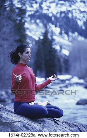Stock Image - Young woman meditating in the lotus position. Fotosearch