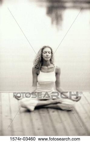 Young woman sitting on a pier meditating View Large Photo Image Stock Image - Young woman sitting on a pier meditating. Fotosearch
