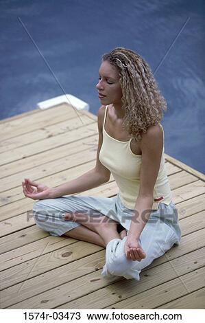 Young woman sitting on a wooden porch meditating View Large Photo Image Stock Image - Young woman sitting on a wooden porch meditating. Fotosearch