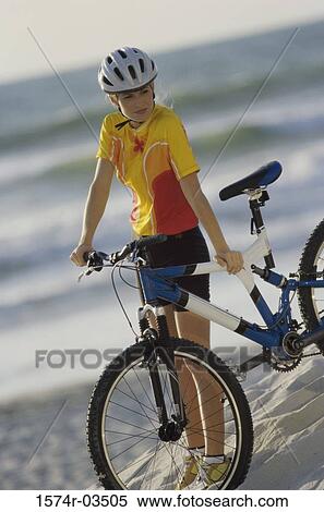 Young woman standing beside a bicycle View Large Photo Image Stock Photography - Young woman standing beside a bicycle. Fotosearch
