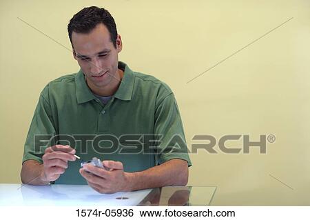 Businessman sitting in an office working on a palmtop View Large Photo Image Stock Photograph - Businessman sitting in an office working on a palmtop. Fotosearch