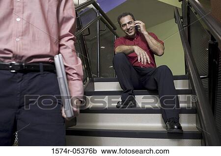 Businessman sitting on stairs talking on a mobile phone View Large Photo Image Stock Image - Businessman sitting on stairs talking on a mobile phone. Fotosearch