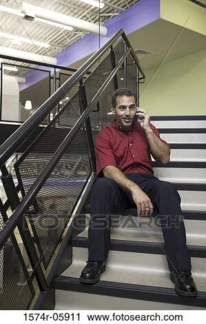 Businessman sitting on stairs talking on a mobile phone View Large Photo Image Stock Image - Businessman sitting on stairs talking on a mobile phone. Fotosearch