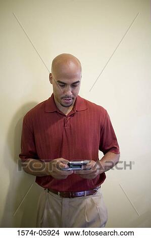 Businessman standing in an office working on a palmtop View Large Photo Image Picture - Businessman standing in an office working on a palmtop. Fotosearch