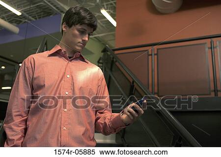 Businessman standing on stairs looking at a palmtop View Large Photo Image Stock Photography - Businessman standing on stairs looking at a palmtop. Fotosearch