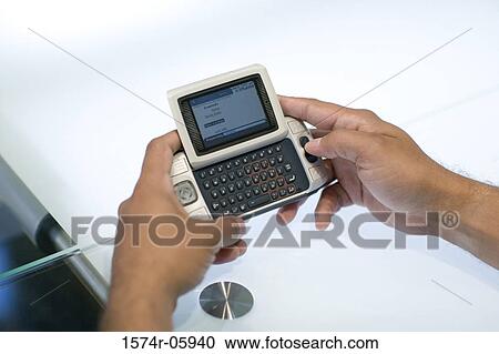 Stock Image - Close-up of a person's hands holding a palmtop. Fotosearch