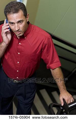 High angle view of a businessman standing on stairs talking on a mobile phone View Large Photo Image Picture - High angle view of a businessman standing on stairs talking on a mobile phone. Fotosearch