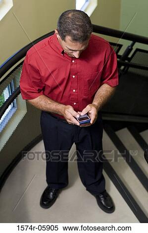 High angle view of a businessman standing on stairs holding a mobile phone View Large Photo Image Stock Photography - High angle view of a businessman standing on stairs holding a mobile phone. Fotosearch