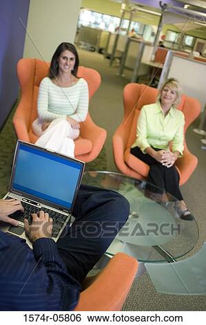 High angle view of two businesswomen sitting on chairs with a businessman sitting in front of them View Large Photo Image Stock Photograph - High angle view of two businesswomen sitting on chairs with a businessman sitting in front of them. Fotosearch