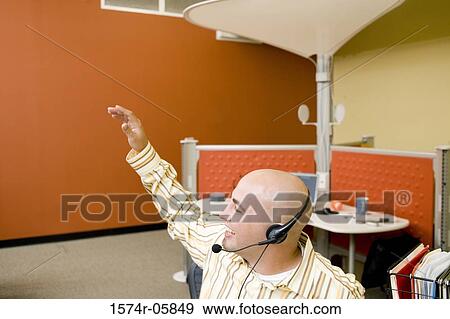 Male customer service representative wearing a headset with his hand raised View Large Photo Image Stock Photo - Male customer service representative wearing a headset with his hand raised. Fotosearch
