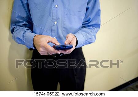 Mid section view of a businessman standing in an office holding a palmtop View Large Photo Image Stock Image - Mid section view of a businessman standing in an office holding a palmtop. Fotosearch
