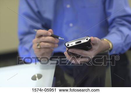 Mid section view of a businessman holding a palmtop View Large Photo Image Stock Image - Mid section view of a businessman holding a palmtop. Fotosearch