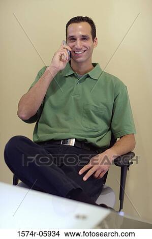 Picture - Portrait of a businessman sitting in an office talking on a mobile phone. Fotosearch