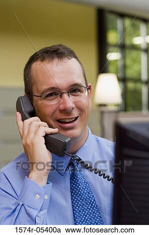 Portrait of a businessman sitting in an office talking on a telephone View Large Photo Image Stock Image - Portrait of a businessman sitting in an office talking on a telephone. Fotosearch
