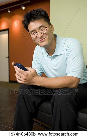Portrait of a businessman sitting in an office holding a mobile phone View Large Photo Image Stock Image - Portrait of a businessman sitting in an office holding a mobile phone. Fotosearch