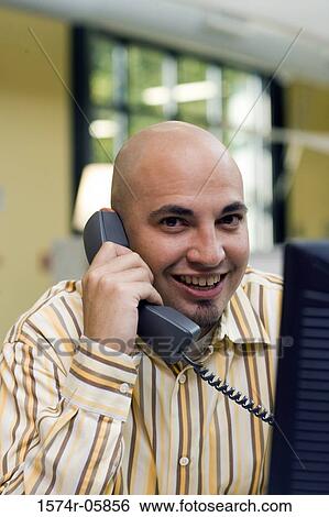 Portrait of a businessman sitting in an office talking on a telephone View Large Photo Image Stock Photograph - Portrait of a businessman sitting in an office talking on a telephone. Fotosearch