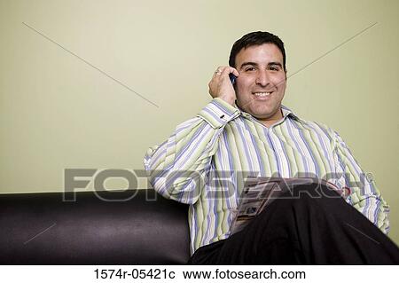 Portrait of a businessman sitting on a couch talking on a mobile phone View Large Photo Image Stock Image - Portrait of a businessman sitting on a couch talking on a mobile phone. Fotosearch