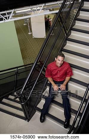 Portrait of a businessman sitting on stairs working on a laptop View Large Photo Image Stock Image - Portrait of a businessman sitting on stairs working on a laptop. Fotosearch