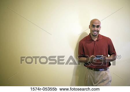 Portrait of a businessman standing in an office holding a palmtop View Large Photo Image Stock Image - Portrait of a businessman standing in an office holding a palmtop. Fotosearch