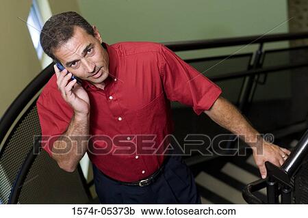 Portrait of a businessman standing on stairs talking on a mobile phone View Large Photo Image Stock Image - Portrait of a businessman standing on stairs talking on a mobile phone. Fotosearch