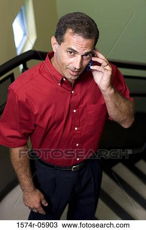 Stock Image - Portrait of a businessman standing on stairs talking on a mobile phone. Fotosearch