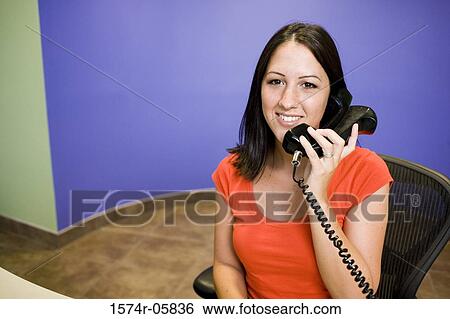 Portrait of a businesswoman sitting in an office talking on a telephone View Large Photo Image Stock Photograph - Portrait of a businesswoman sitting in an office talking on a telephone. Fotosearch
