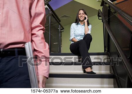 Stock Image - Portrait of a businesswoman sitting on stairs talking on a mobile phone. Fotosearch