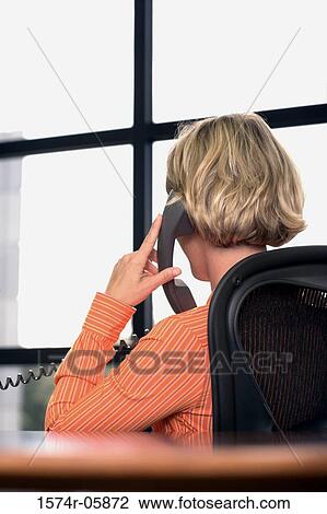 Rear view of a businesswoman sitting in an office talking on a telephone View Large Photo Image Stock Image - Rear view of a businesswoman sitting in an office talking on a telephone. Fotosearch