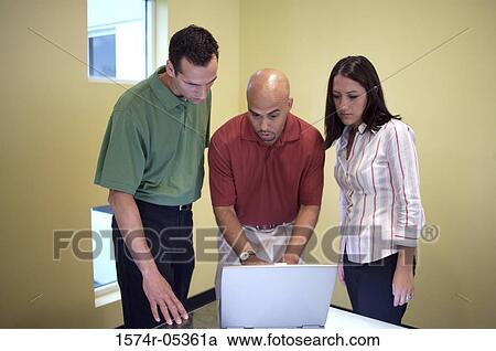 Two businessmen and a businesswoman looking at a laptop View Large Photo Image Stock Image - Two businessmen and a businesswoman looking at a laptop. Fotosearch