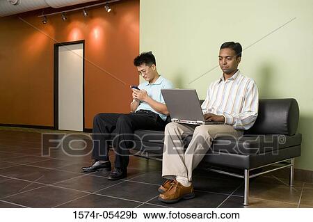 Two businessmen sitting on a couch View Large Photo Image Stock Image - Two businessmen sitting on a couch. Fotosearch