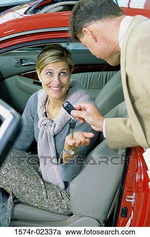 Car salesman giving the car keys to a mid adult woman View Large Photo Image Stock Image - Car salesman giving the car keys to a mid adult woman. Fotosearch