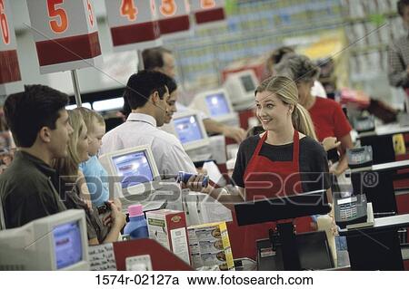 Stock Image - Customers standing at a checkout counter in a supermarket. Fotosearch