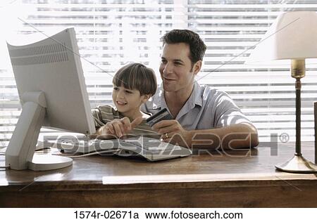 Stock Image - Father and his son sitting in front of a computer. Fotosearch