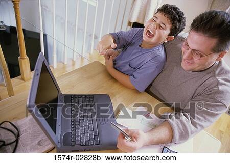 High angle view of a father and his son sitting in front of a laptop holding a credit card View Large Photo Image Stock Image - High angle view of a father and his son sitting in front of a laptop holding a credit card. Fotosearch