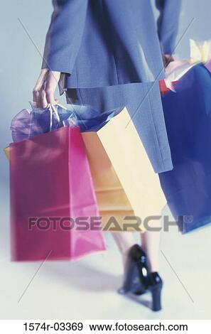 Low section view of a woman carrying shopping bags View Large Photo Image Stock Photo - Low section view of a woman carrying shopping bags. Fotosearch