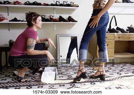 Stock Photo - Low section view of a young woman trying on sandals in a shoe store. Fotosearch