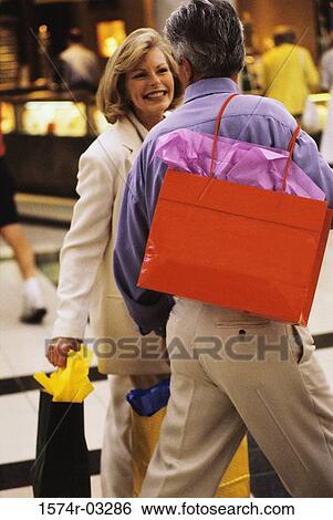 Stock Photograph - Mature couple walking with shopping bags. Fotosearch