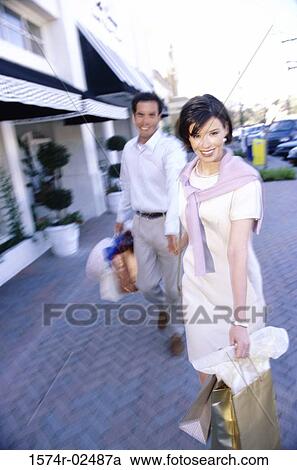 Mid adult couple carrying shopping bags View Large Photo Image Stock Image - Mid adult couple carrying shopping bags. Fotosearch