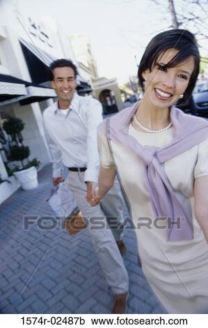 Mid adult couple carrying shopping bags View Large Photo Image Stock Image - Mid adult couple carrying shopping bags. Fotosearch