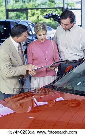 Mid adult couple looking at a brochure in a car showroom View Large Photo Image Stock Image - Mid adult couple looking at a brochure in a car showroom. Fotosearch