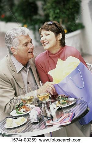 Stock Photo - Mid adult couple sitting at a table. Fotosearch