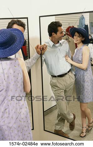 Mid adult couple standing in front of a mirror in the fitting room of a clothing store View Large Photo Image Stock Image - Mid adult couple standing in front of a mirror in the fitting room of a clothing store. Fotosearch