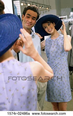 Mid adult couple standing in front of a mirror in the fitting room of a clothing store View Large Photo Image Stock Image - Mid adult couple standing in front of a mirror in the fitting room of a clothing store. Fotosearch